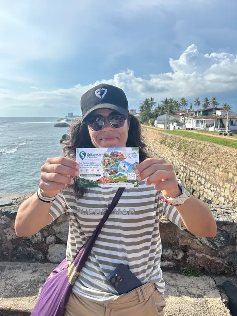 A traveller on the Galle Fort ramparts holding a Srilankan Guide card