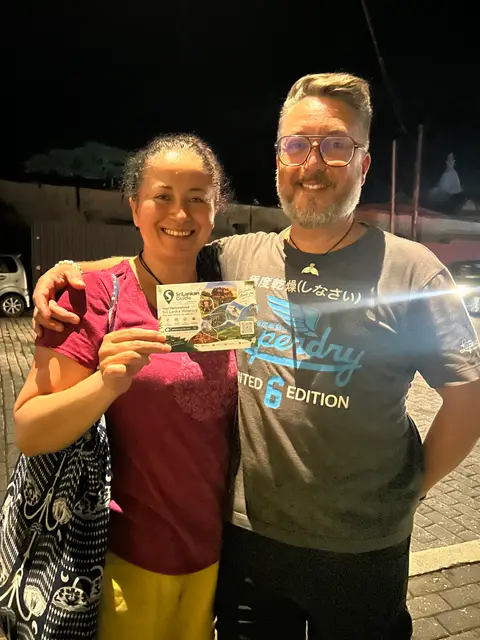 Two travellers in Galle Fort in the evening, holding a Srilankan Guide card