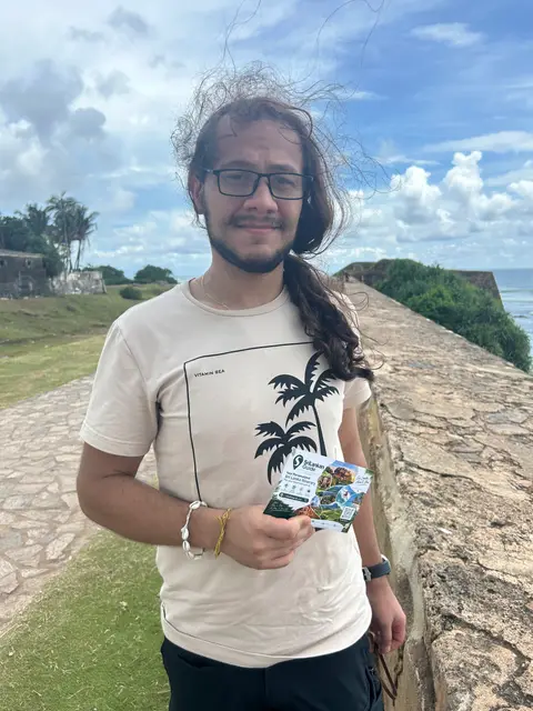 A traveller on the Galle Fort walls holding a Srilankan Guide card