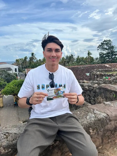 A traveller sitting on the Galle Fort walls holding a Srilankan Guide card